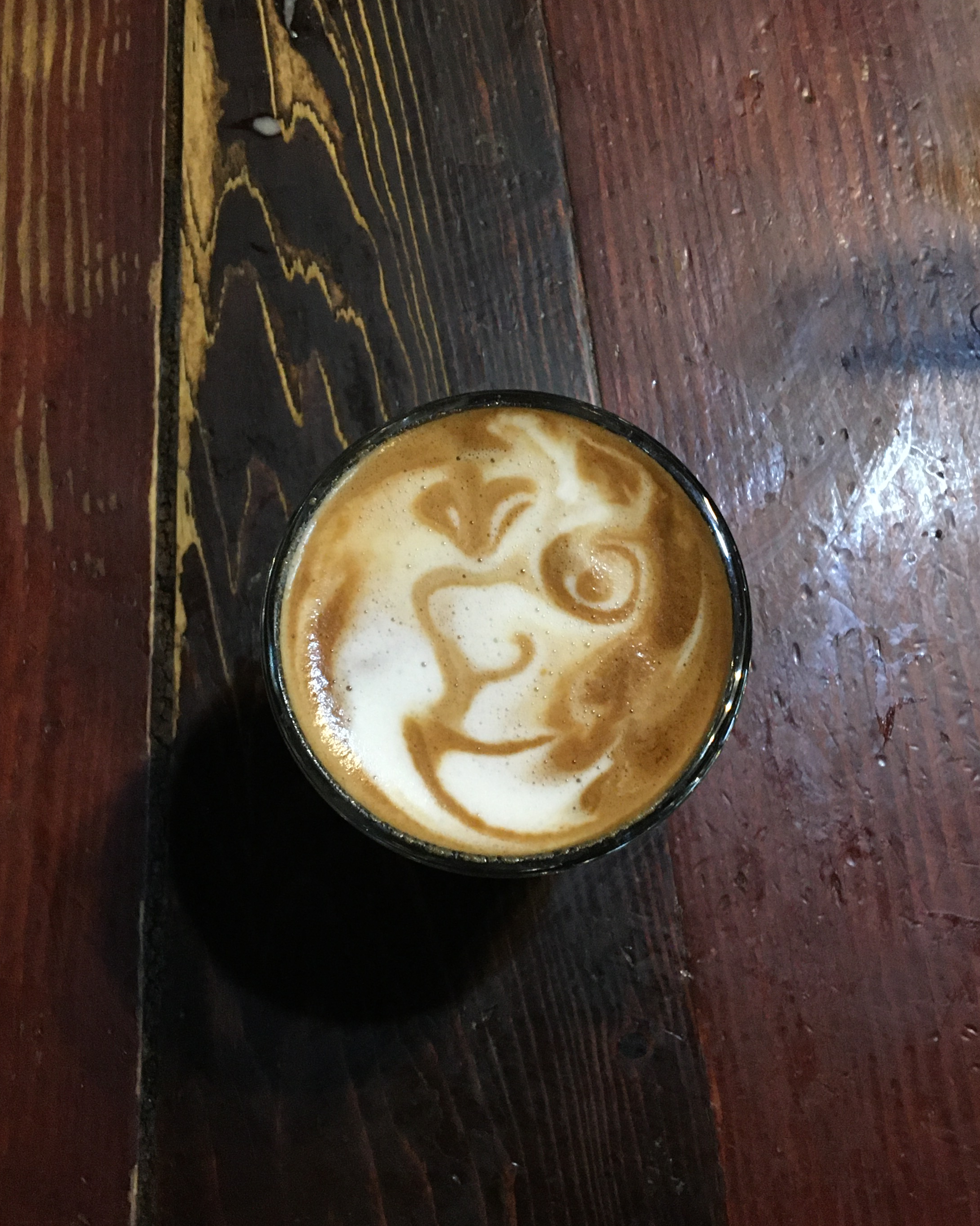 latte art in a small glass of a picasso style face