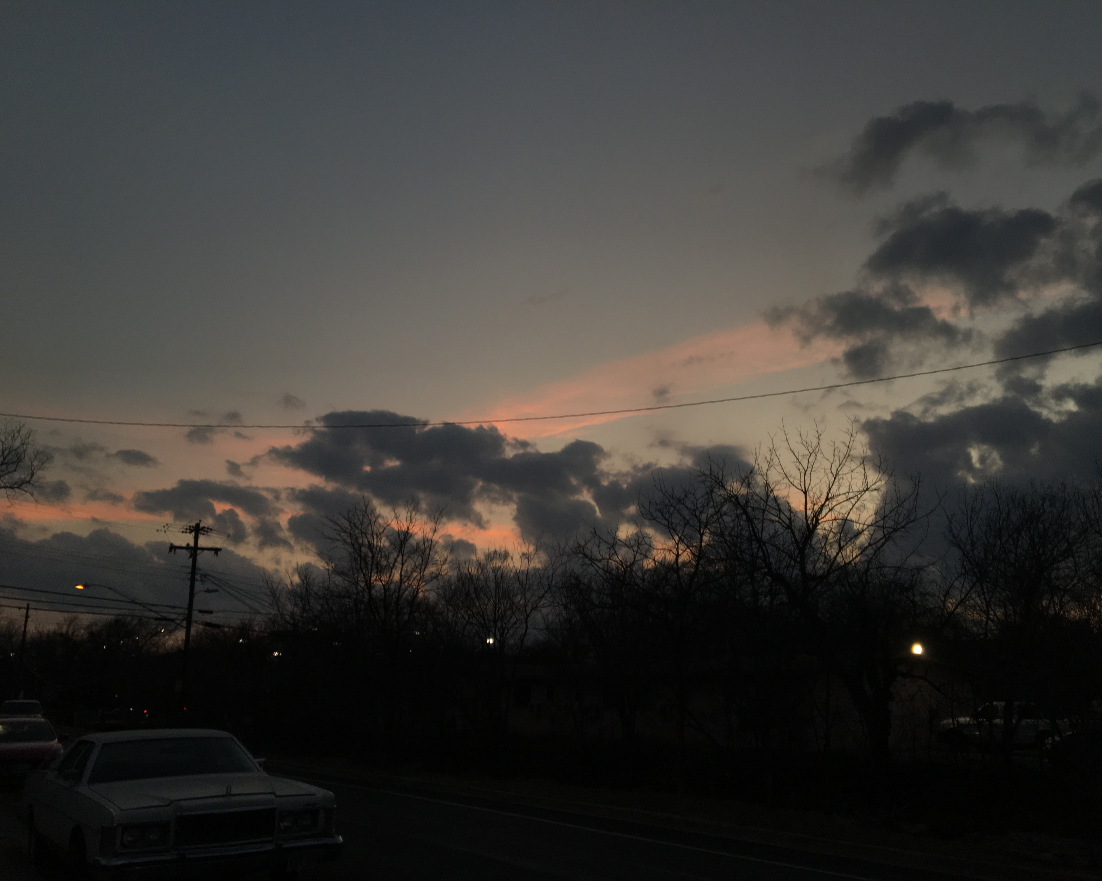 photo of a mild, mostly blue + yellow  sunset with the silhouette of some powerlines visible in the foreground